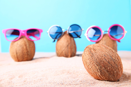Coconuts with sunglasses on the beach sandの写真素材