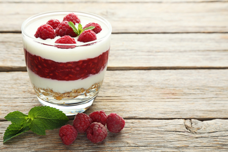 Dessert with raspberries and granola in glasses on grey wooden tableの写真素材