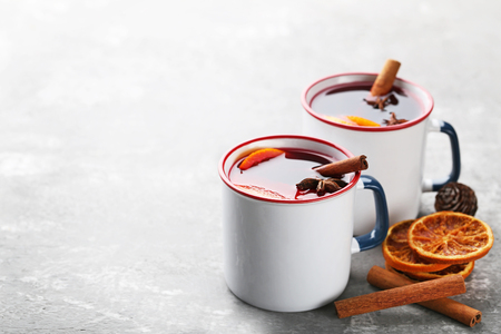 Mulled wine in mugs with spices on wooden tableの写真素材