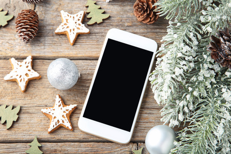 Smartphone with gingerbread cookies and fir-tree branches on wooden tableの写真素材