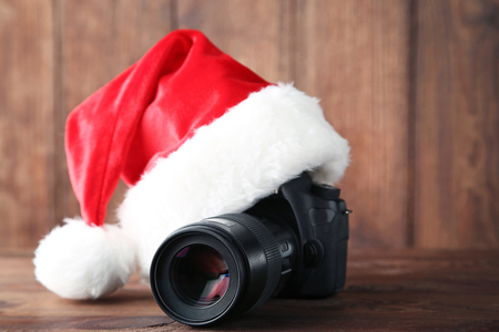 Red santa hat with camera on grey wooden tableの写真素材