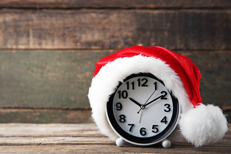 Red santa hat with clock on grey wooden table
