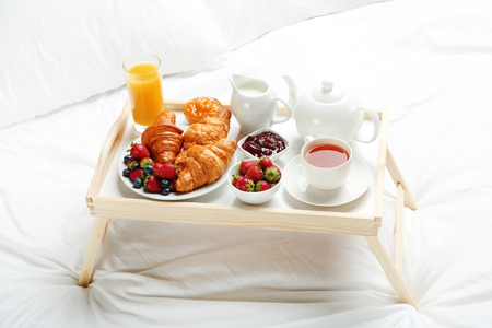 Tasty breakfast in bed on wooden trayの写真素材
