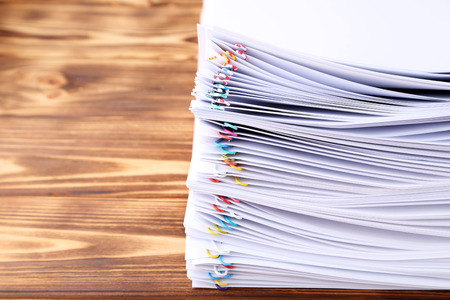 Stack of papers with paperclips on wooden table