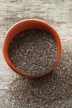Heap of chia seeds in bowl on wooden tableの写真素材