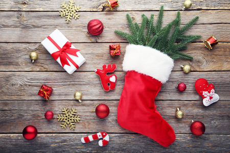 Red stocking with fir-tree branches and christmas decorations on wooden tableの写真素材