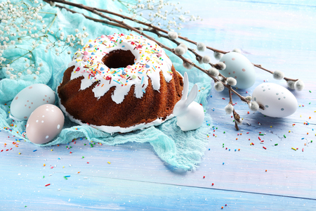 Bundt cake with sprinkles and easter eggs on blue wooden tableの写真素材