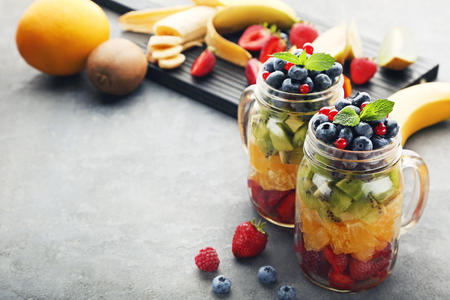 Fresh fruit salad in jars on grey wooden tableの写真素材