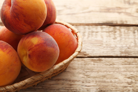 Ripe peaches fruit in basket on wooden tableの写真素材