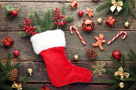 Red stocking with fir-tree branches and christmas decorations on wooden table