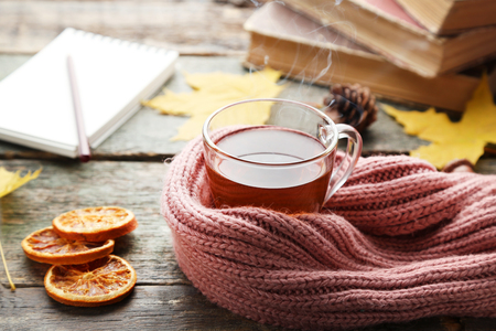 Cup of tea with pink scarf and dry oranges on wooden tableの写真素材