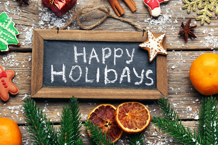 Inscription Happy Holiday on wooden frame with mandarins and gingerbread cookiesの写真素材