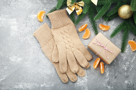 Knitted beige gloves with mandarins and fir-tree branches on wooden tableの写真素材