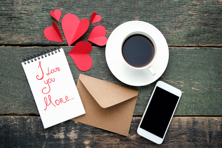 Red paper hearts with smartphone and cup of coffee on wooden tableの写真素材