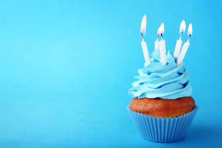 Tasty cupcake with candles on blue backgroundの写真素材