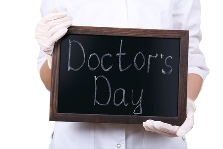 Female hands holding wooden frame with inscription Doctor's Dayの写真素材
