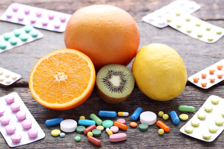 Ripe fruits and colorful pills on wooden tableの写真素材