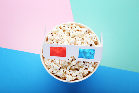 Popcorn in striped bucket with glasses on colorful backgroundの写真素材