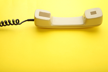 Beige telephone handset on yellow backgroundの写真素材