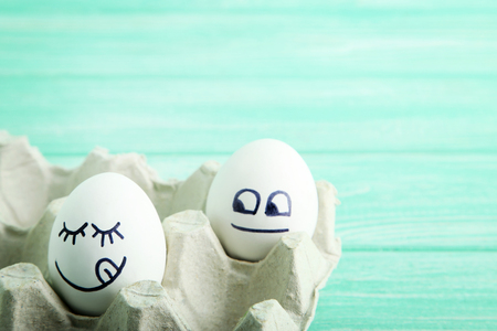 Eggs with funny faces in carton packageの写真素材