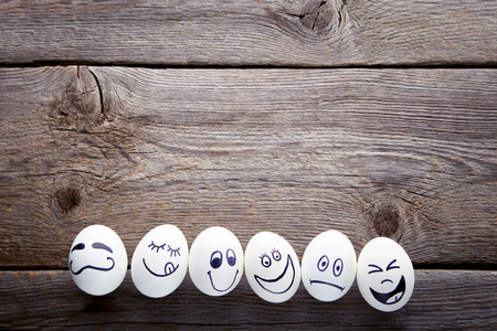 Eggs with funny faces on grey wooden tableの写真素材