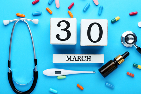 Calendar cubes with pills, stethoscope and thermometer on blue backgroundの写真素材