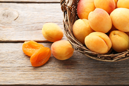 Sweet apricots in basket on grey wooden tableの写真素材
