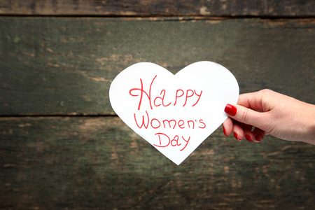 Female hand holding card with inscription Happy women's dayの写真素材