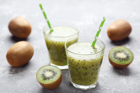 Fresh kiwi smoothie in glass on grey wooden tableの写真素材