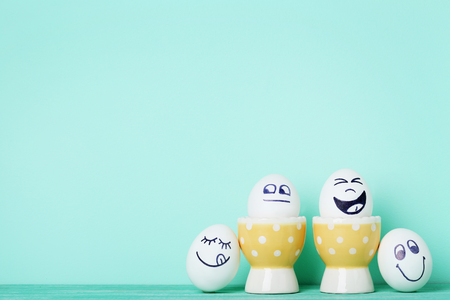 Eggs with funny faces on mint backgroundの写真素材
