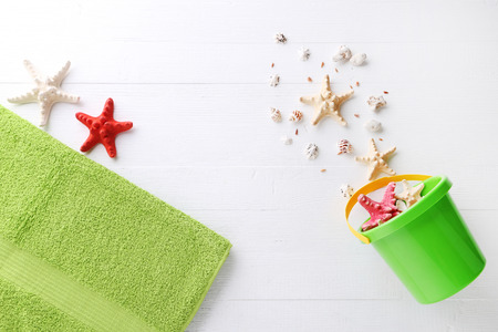 Green bucket with seashells on white wooden tableの写真素材
