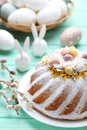 Easter cake with eggs and ceramic rabbits on mint wooden tableの写真素材