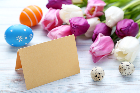 Blank card with painted eggs and tulips on wooden tableの写真素材
