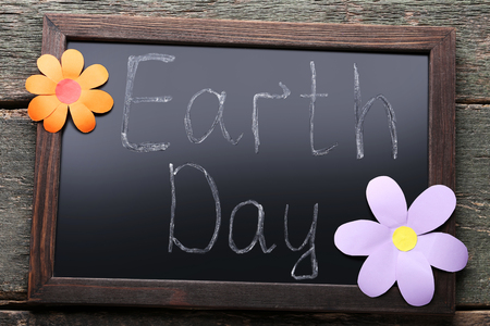 Inscription Earth Day on wooden frame with paper flowersの写真素材