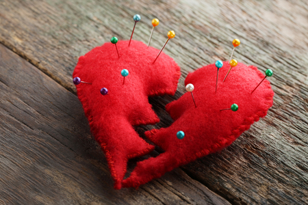Broken red heart with needles on grey wooden tableの写真素材