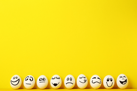 Eggs with funny faces on yellow backgroundの写真素材