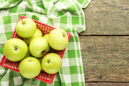 Ripe green apples in basket on wooden tableの写真素材