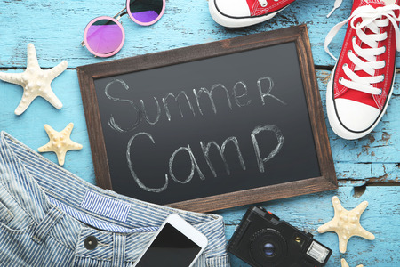 Inscription Summer Camp with smartphone, sunglasses and clothes on wooden tableの写真素材
