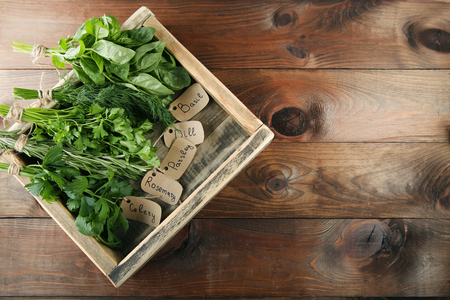 Different fresh herbs in box on brown wooden tableの写真素材