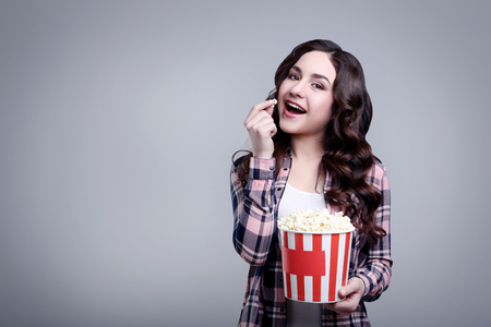 Young beautiful woman holding bucket with popcorn on grey backgroundの写真素材
