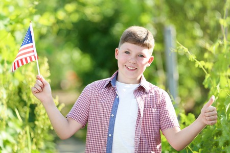 Young boy holding american flag in the gardenの写真素材