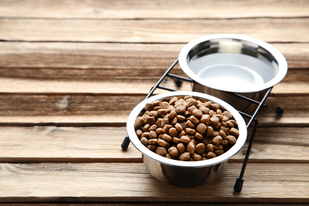 Cat food and water in bowls on wooden tableの写真素材