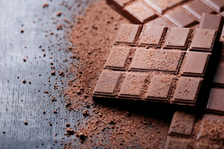 Chocolate bars with cocoa powder on wooden tableの写真素材