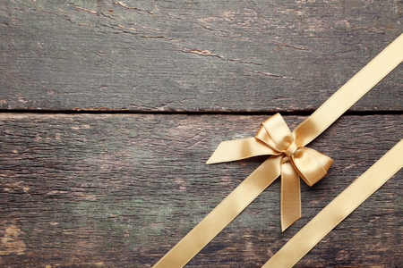 Golden bow with ribbon on grey wooden tableの写真素材