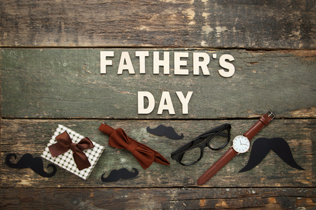 Inscription Fathers Day with accesories and gift box on wooden tableの写真素材