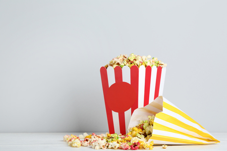 Sweet popcorn in striped bucket and paper bag on grey backgroundの写真素材