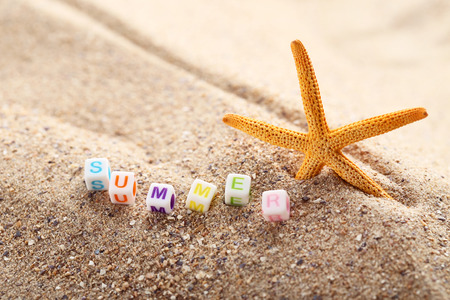 Inscription Summer by cubes and starfish on beach sandの写真素材