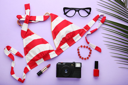 Swimsuit with cosmetics and camera on purple backgroundの写真素材