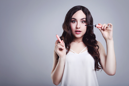 Beautiful woman with mascara on grey backgroundの写真素材