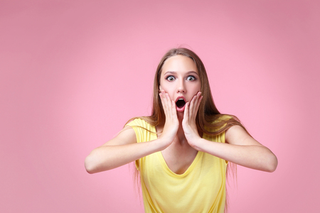 Portrait of emotional young woman on pink backgroundの写真素材